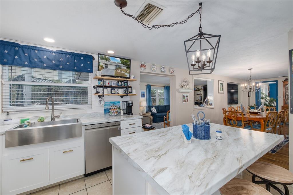 A kitchen with a marble-topped island, stainless steel farmhouse sink, and open dining area — 8225 SAN FELIPE COURT, PORT RICHEY, FL