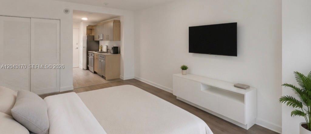 A bedroom with a bed, a wall-mounted television, a media console, and an adjacent kitchen — 10275 Collins Ave # 115, Bal Harbour FL 33154, BAL HARBOUR, FL