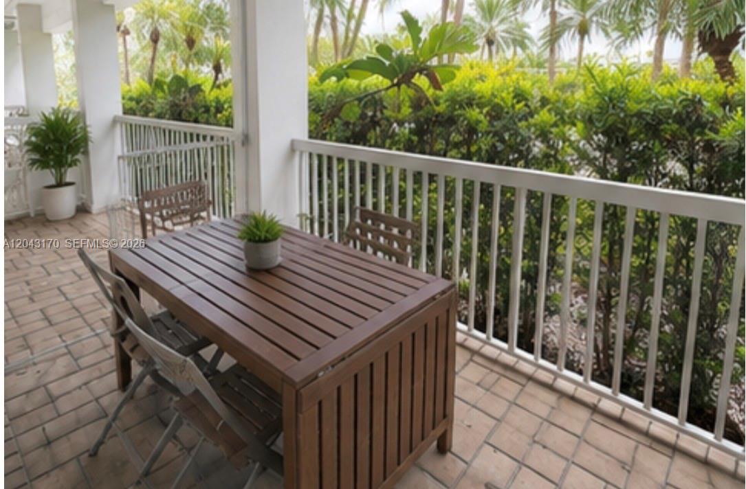A wooden dining table and chairs sit on a tiled balcony with white railings — 10275 Collins Ave # 115, Bal Harbour FL 33154, BAL HARBOUR, FL