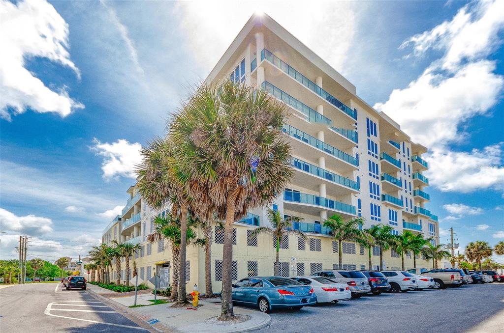A multi-story apartment building with glass balconies and palm trees in a parking lot — 15 AVALON STREET UNIT 702, CLEARWATER BEACH, FL