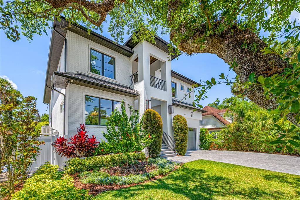 A two-story white brick house with a dark metal roof and a paved driveway — 2623 S PARKVIEW STREET, TAMPA, FL