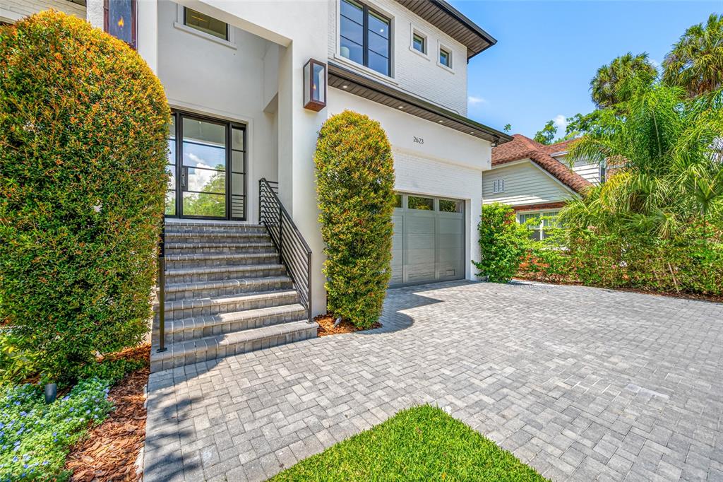 The exterior of a modern white house features a brick staircase, garage, and paved driveway — 2623 S PARKVIEW STREET, TAMPA, FL