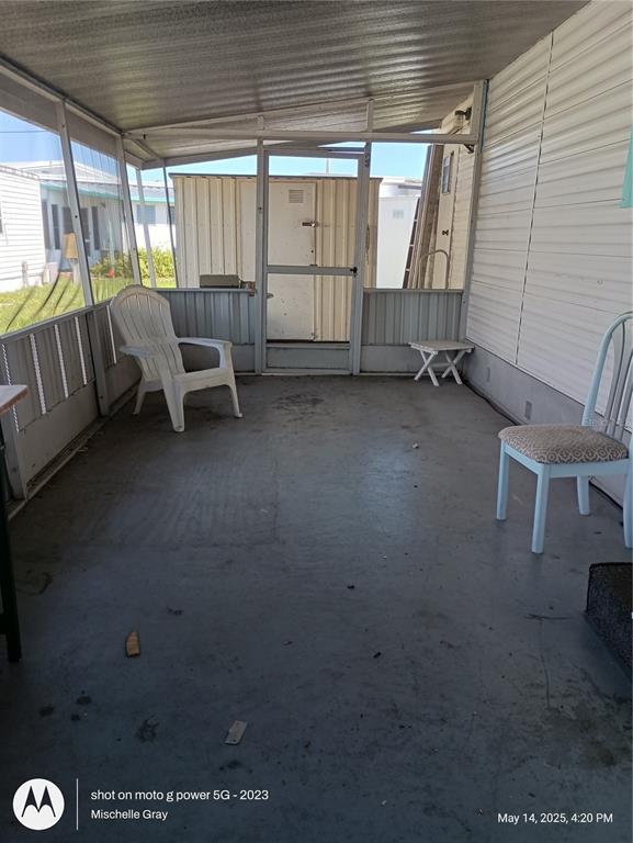 A screened-in porch with a concrete floor, two chairs, and a small side table — 1714 FLORIDA BOULEVARD, BRADENTON, FL