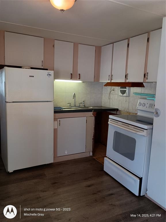 A kitchen features white cabinets, a white refrigerator, a white stove, and wood-look flooring — 1714 FLORIDA BOULEVARD, BRADENTON, FL