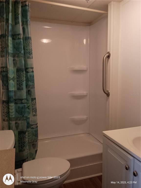 A bathroom features a white shower stall with built-in shelves, a grab bar, and a toilet — 1714 FLORIDA BOULEVARD, BRADENTON, FL