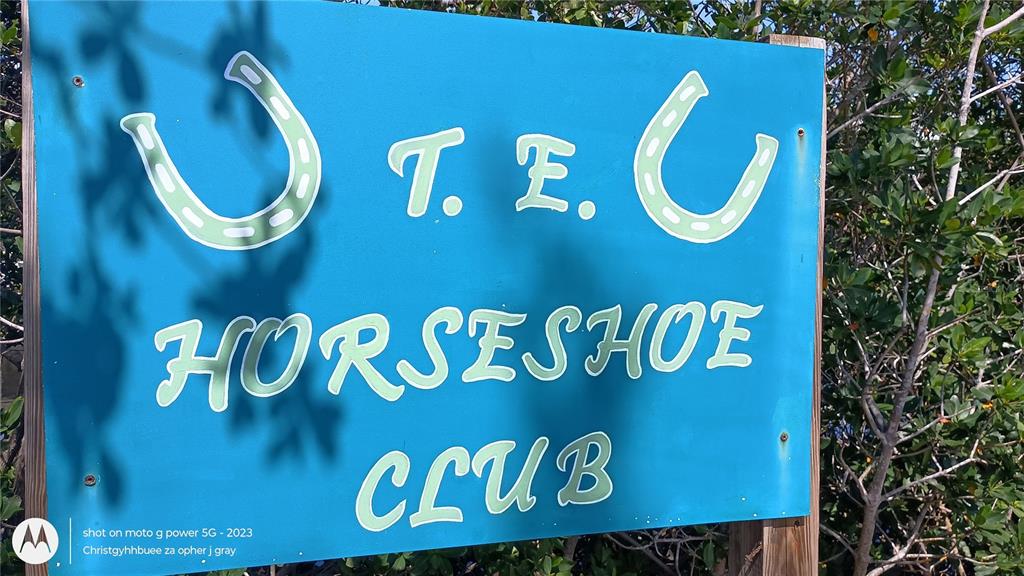 A blue sign for the T.E. Horseshoe Club stands outdoors near some trees — 1714 FLORIDA BOULEVARD, BRADENTON, FL