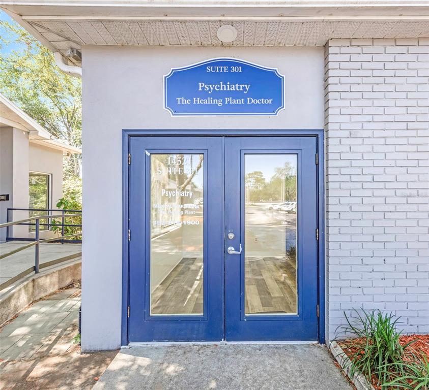 The exterior entrance to a psychiatry office features double blue doors and a suite sign — 14517 BRUCE B DOWNS BOULEVARD UNIT 301, TAMPA, FL