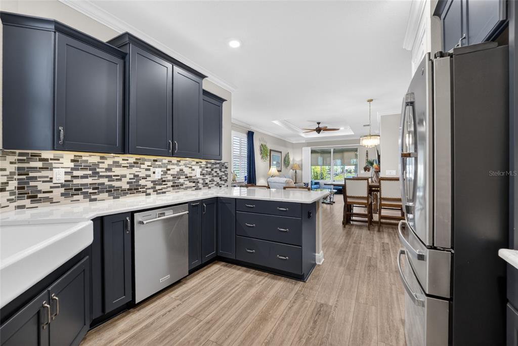 A kitchen features dark blue cabinets, stainless steel appliances, and a mosaic tile backsplash — 10363 SW 96TH LOOP, OCALA, FL
