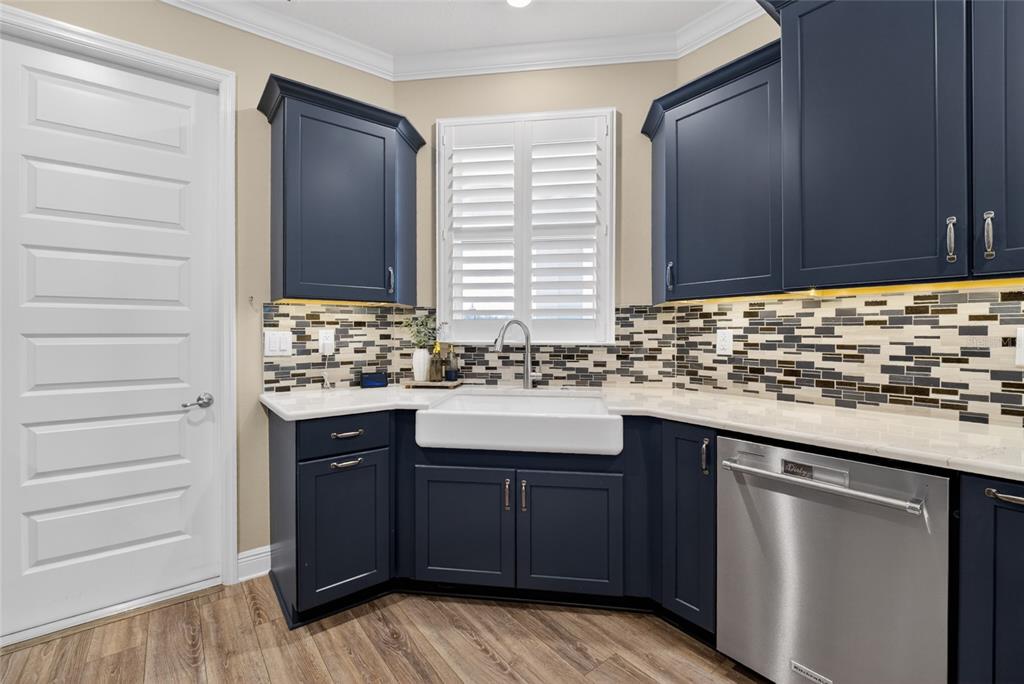 A kitchen features dark blue cabinets, a white farmhouse sink, and a mosaic tile backsplash — 10363 SW 96TH LOOP, OCALA, FL