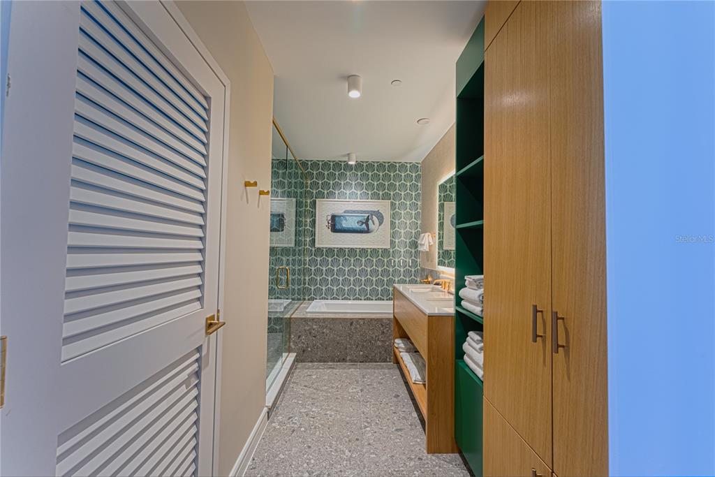 A bathroom features a soaking tub, a double vanity, and green shelving with wood cabinets — 8061 VACATION AVENUE UNIT 309, KISSIMMEE, FL