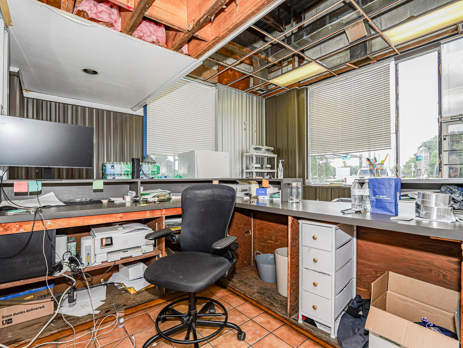 A cluttered office space features an exposed ceiling, metal wall panels, and a built-in desk — 415 S Us Highway 1, Vero Beach FL 32962, VERO BEACH, FL