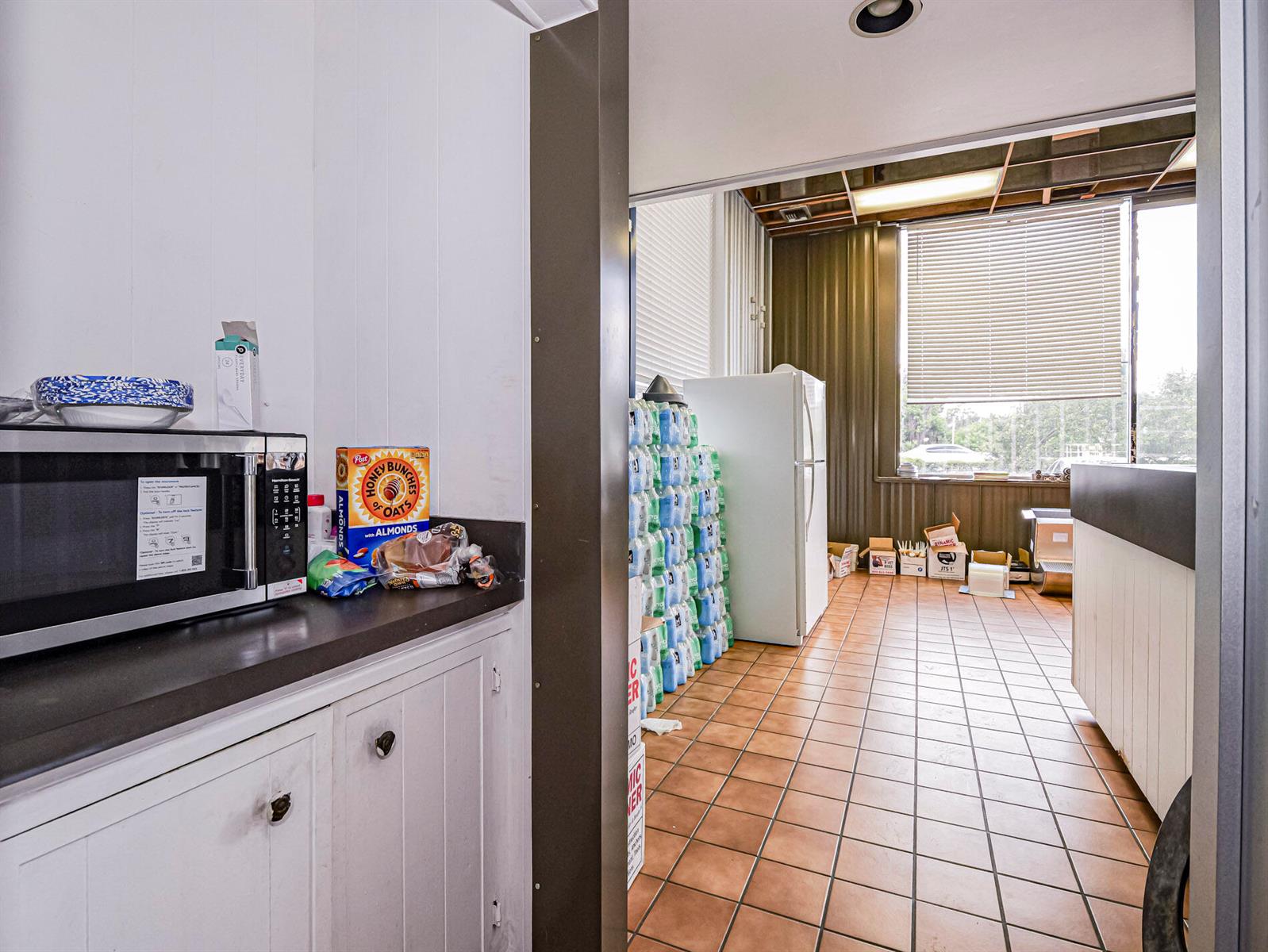 A small kitchen area with a microwave leads into a tiled room with storage — 415 S Us Highway 1, Vero Beach FL 32962, VERO BEACH, FL
