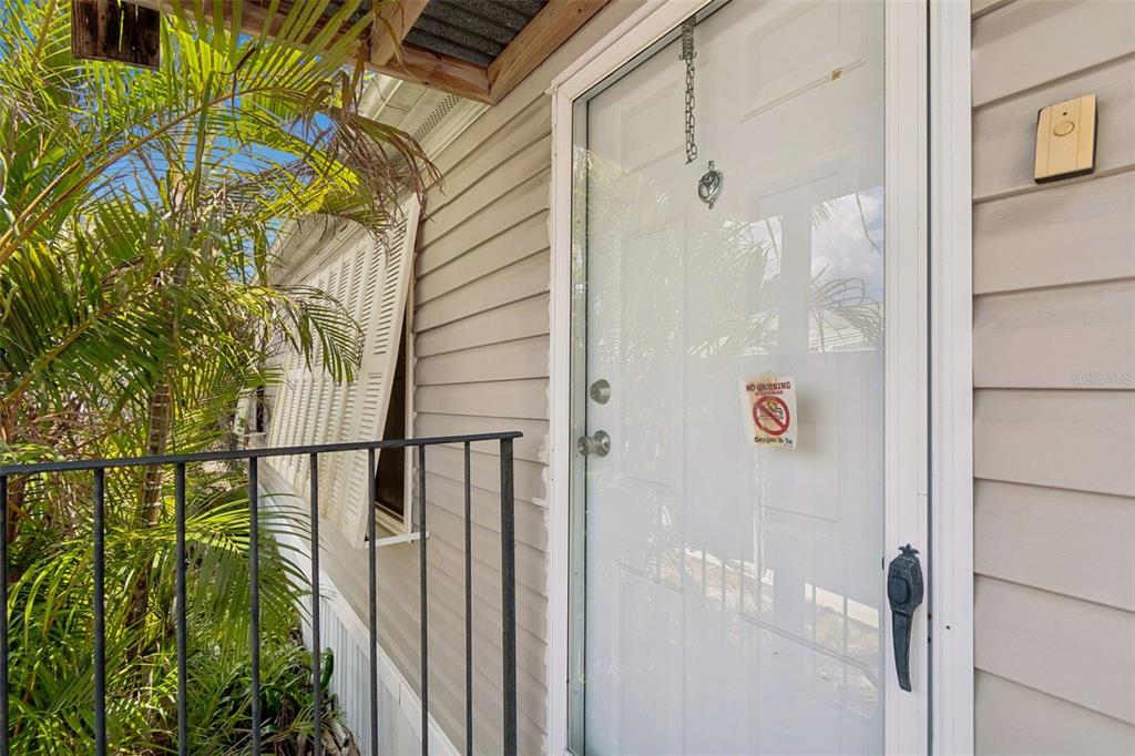A white storm door with a no-smoking sign leads to the entrance of a house — 12701 126TH AVENUE UNIT 63, LARGO, FL