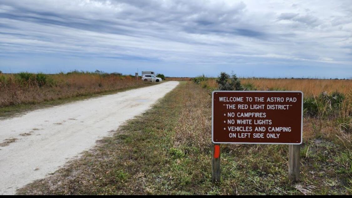 A sign at a dirt road entrance lists rules for an astronomy camping area — 0 NW 302, Okeechobee FL 34972, OKEECHOBEE, FL