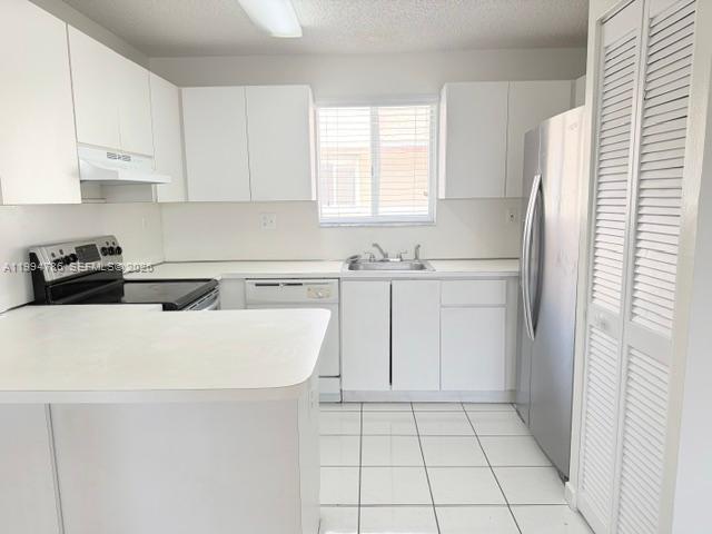 A kitchen with white cabinets, white countertops, stainless steel appliances, and white tile flooring — 3260 W 70th St # 202, Hialeah FL 33018, HIALEAH, FL