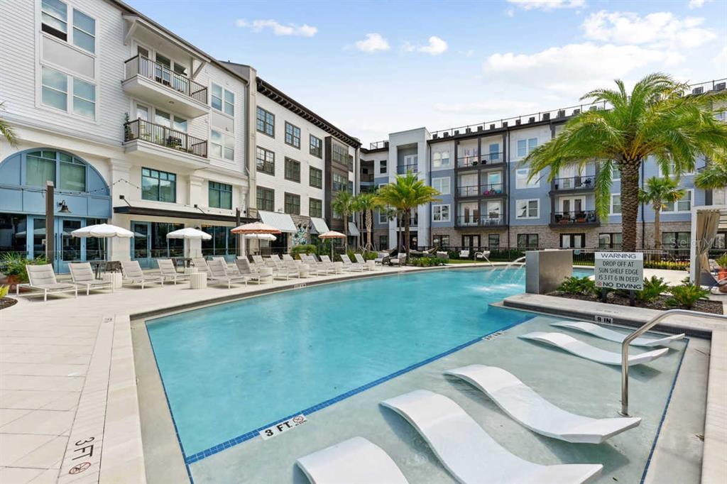 A swimming pool with a sun shelf and lounge chairs sits between two apartment buildings — 1464 LAUREL SOUND LANE UNIT B5, SANFORD, FL