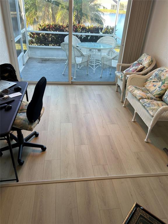 A room with light wood-look flooring features a desk, wicker seating, and a sliding glass door — 1830 SAN SILVESTRO DRIVE, VENICE, FL
