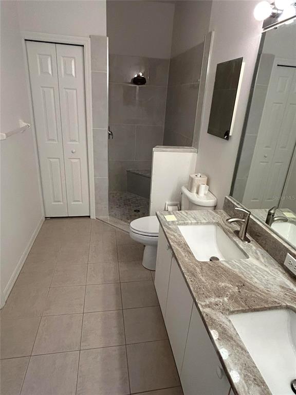 A bathroom features a double vanity with stone countertops, a tiled shower, and tile flooring — 1830 SAN SILVESTRO DRIVE, VENICE, FL