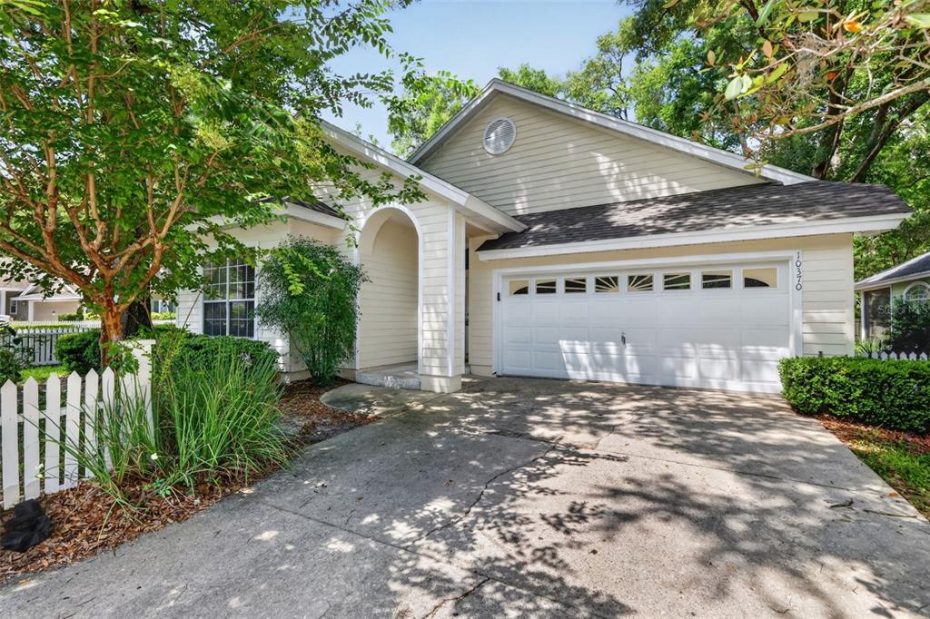 A single-story house with light siding, a white garage door, and a white picket fence — 10370 SW 51ST LANE, GAINESVILLE, FL