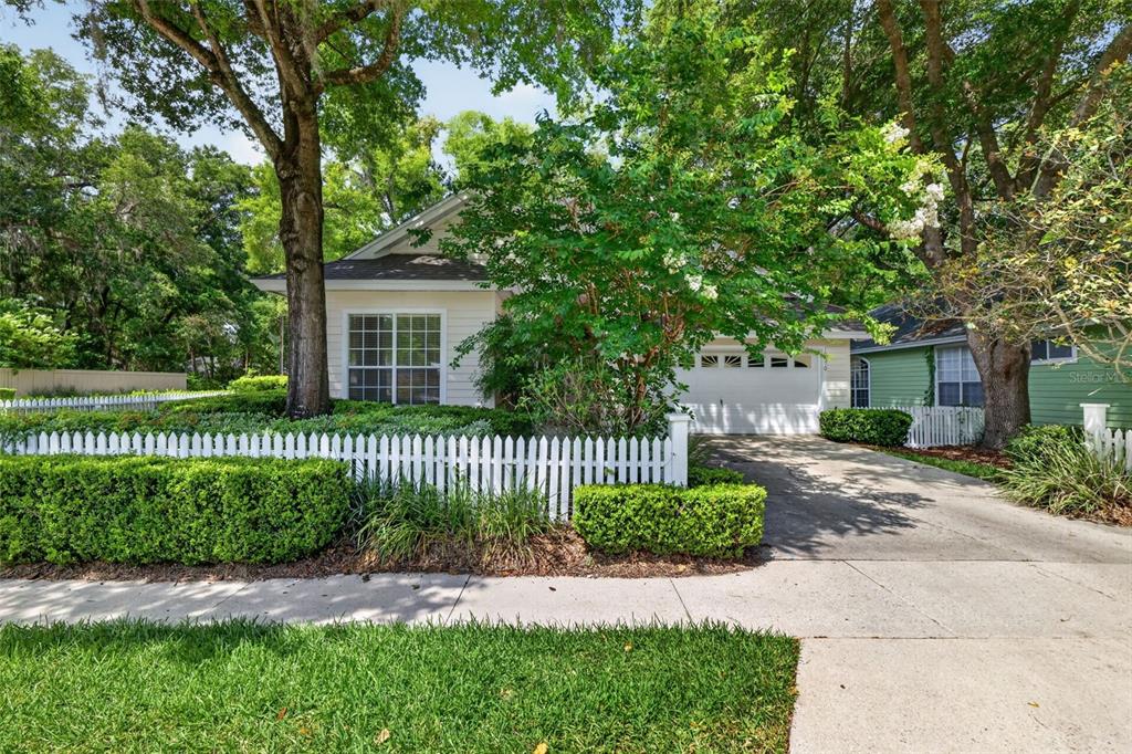 A single-story house with a white picket fence, a paved driveway, and mature trees — 10370 SW 51ST LANE, GAINESVILLE, FL
