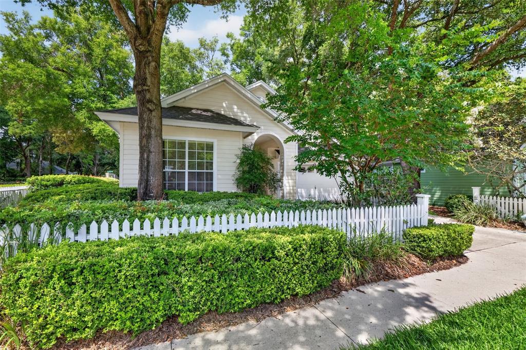 A single-story house with light siding, a white picket fence, and mature landscaping — 10370 SW 51ST LANE, GAINESVILLE, FL