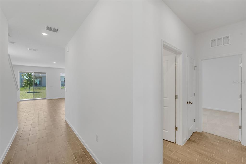 A hallway with tile flooring leads to a living area with sliding glass doors — 874 SUNSHOWER DRIVE, LADY LAKE, FL