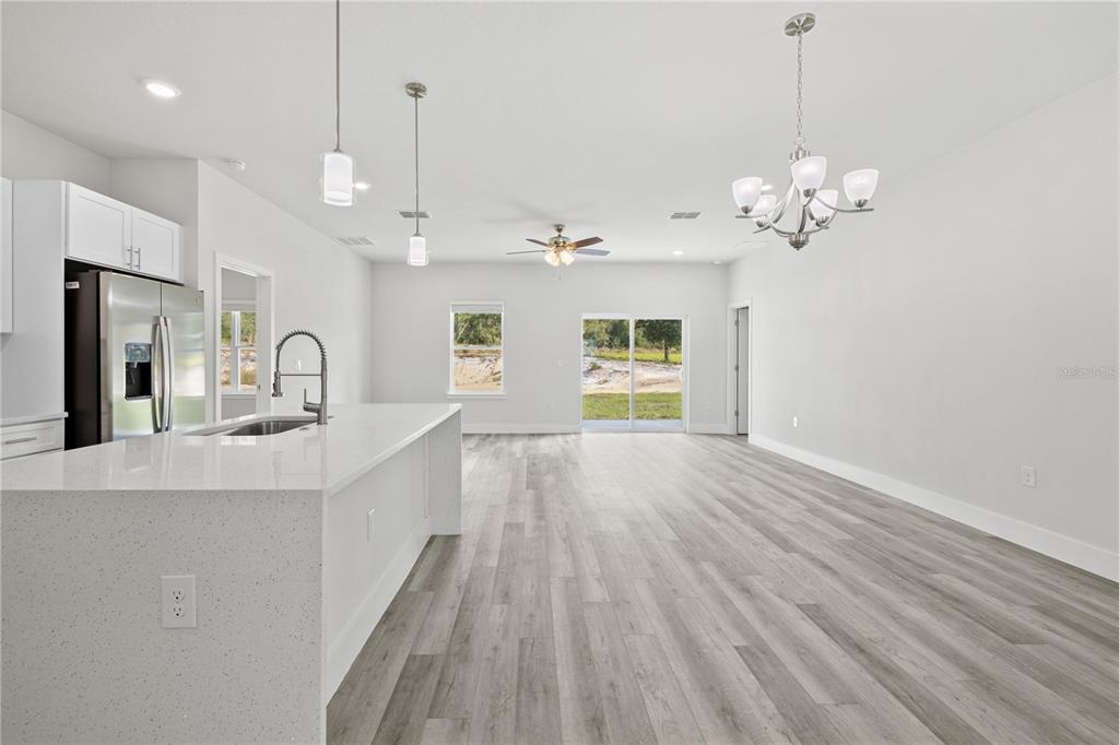 An open-concept kitchen and living area features white cabinetry, a quartz island, and wood-look flooring — 16616 SW 31ST CIRCLE, OCALA, FL