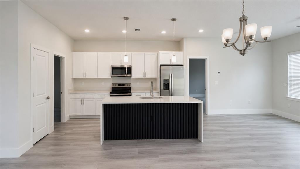 A modern kitchen features white cabinets, stainless steel appliances, and a black-paneled kitchen island — 16616 SW 31ST CIRCLE, OCALA, FL