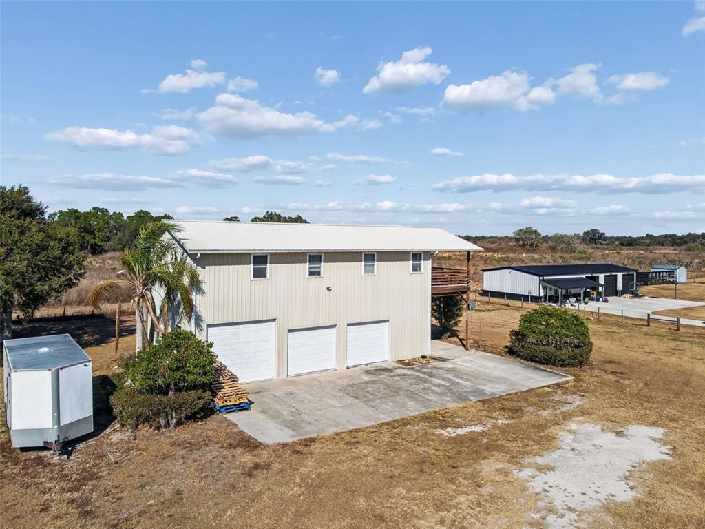 An exterior view of a two-story metal building with three garage doors and a balcony — 4026 MCINTOSH ESTATES LANE, PLANT CITY, FL