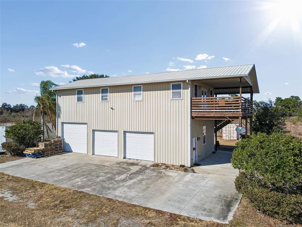 An exterior view of a two-story metal building with three garage doors and a balcony — 4026 MCINTOSH ESTATES LANE, PLANT CITY, FL