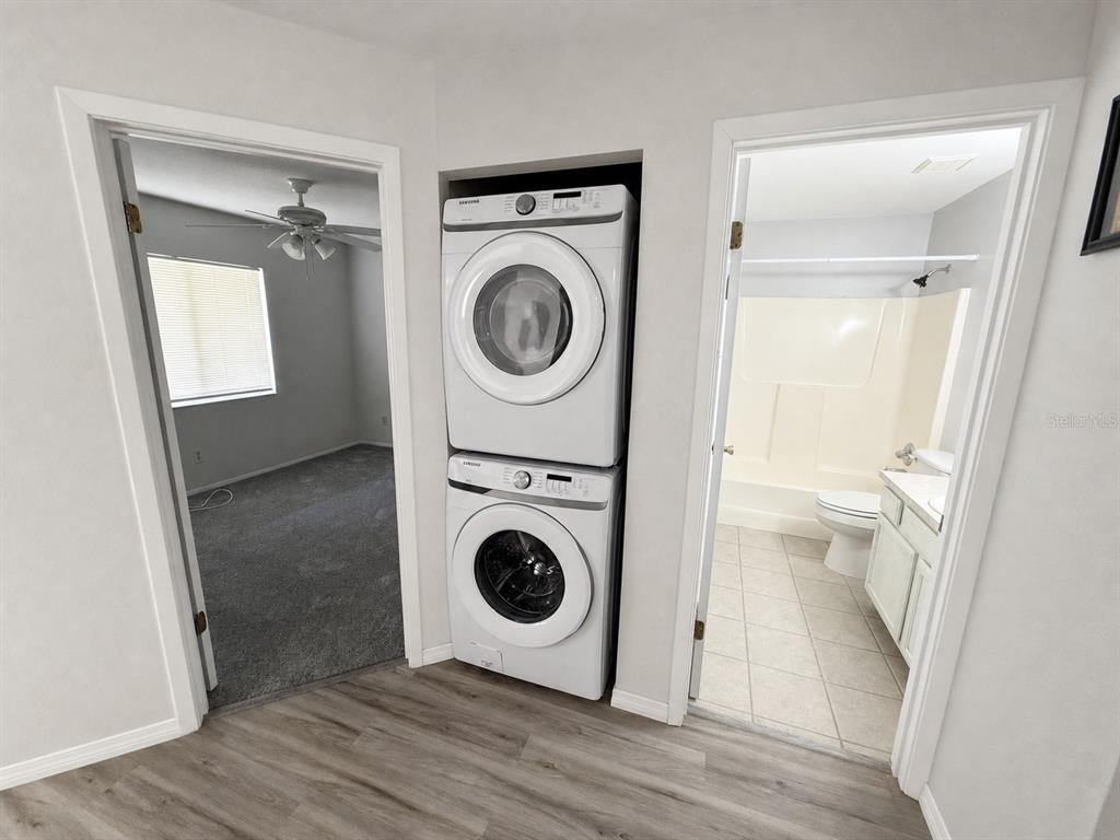 A stacked washer and dryer unit sits between a bedroom doorway and a bathroom doorway — 7904 WATERVIEW WAY, WINTER HAVEN, FL