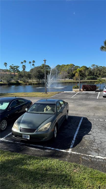 A gray sedan is parked in a lot next to a pond with a fountain — 4640 WEYBRIDGE UNIT 12, SARASOTA, FL