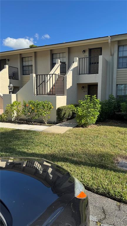 A two-story tan stucco apartment building features exterior staircases and small balconies — 4640 WEYBRIDGE UNIT 12, SARASOTA, FL