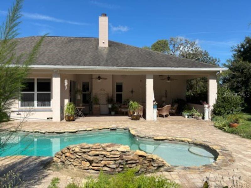 A house with a covered patio and a stone-bordered swimming pool in the backyard — 1521 SHADOW PINES DRIVE, NEW SMYRNA BEACH, FL