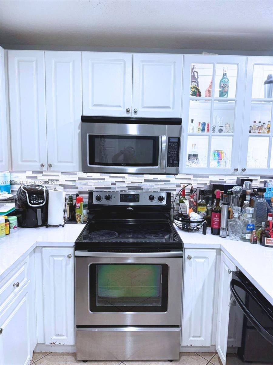 A kitchen features white cabinets, stainless steel appliances, and a tiled backsplash — 22711 SW 88th Pl # 23, Cutler Bay FL 33190, CUTLER BAY, FL