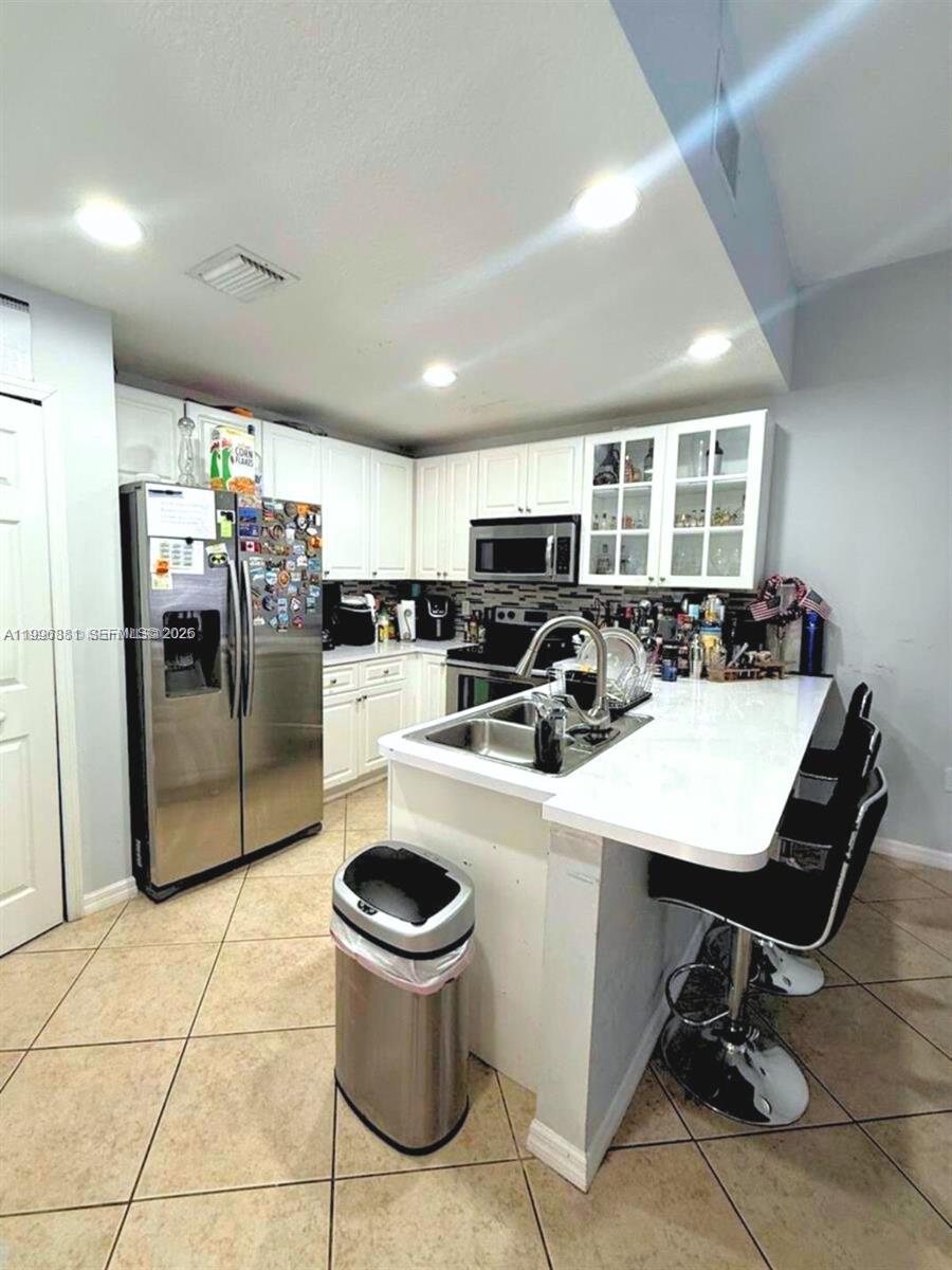 A kitchen features white cabinets, stainless steel appliances, a center island, and tiled flooring — 22711 SW 88th Pl # 23, Cutler Bay FL 33190, CUTLER BAY, FL