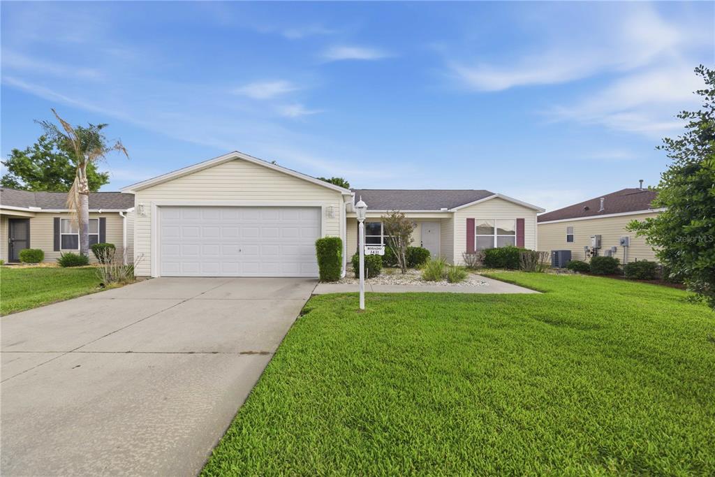 A single-story house with light siding, a two-car garage, and a front lawn — 3431 SIPSEY STREET, THE VILLAGES, FL
