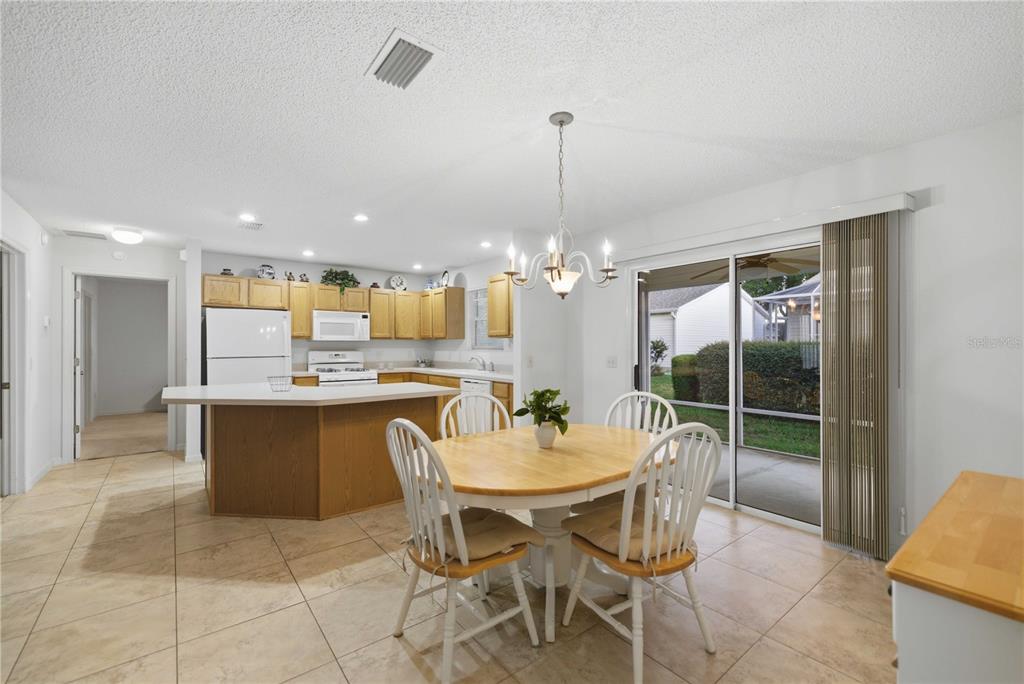 A kitchen and dining area with light wood cabinets, tile floors, and a sliding glass door — 3431 SIPSEY STREET, THE VILLAGES, FL