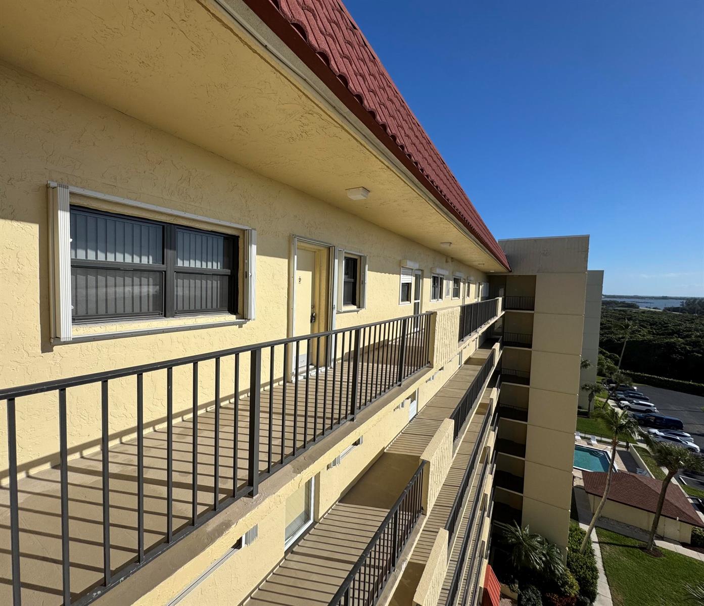 An exterior view of a multi-story apartment building with yellow stucco walls and metal railings — 7430 S Ocean Drive # 818, Jensen Beach FL 34957, JENSEN BEACH, FL