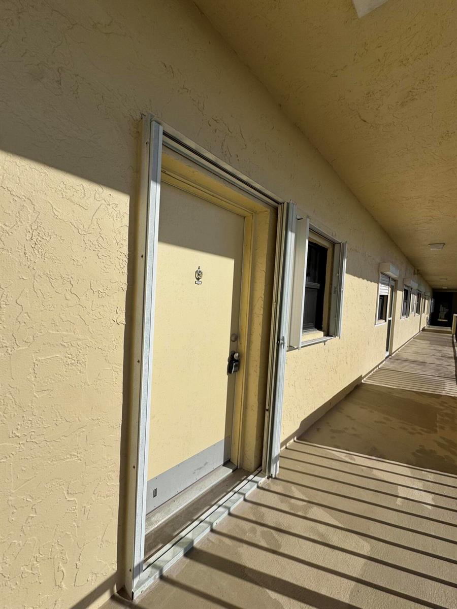 An exterior view of a yellow building hallway with a door and a window — 7430 S Ocean Drive # 818, Jensen Beach FL 34957, JENSEN BEACH, FL