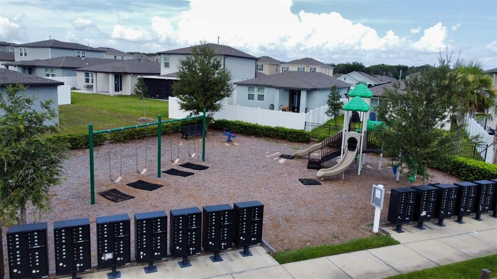 An aerial view shows a playground with a swing set and slide near community mailboxes — 3336 CURLEW AVENUE, LEESBURG, FL