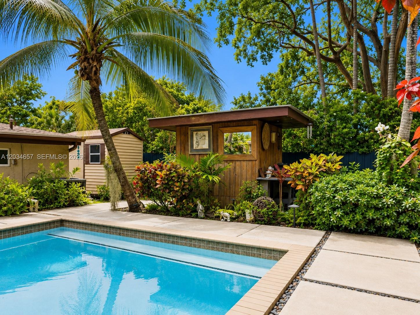 A backyard swimming pool sits next to a wooden tiki bar and a small shed — 1850 Keystone Blvd, North Miami FL 33181, NORTH MIAMI, FL