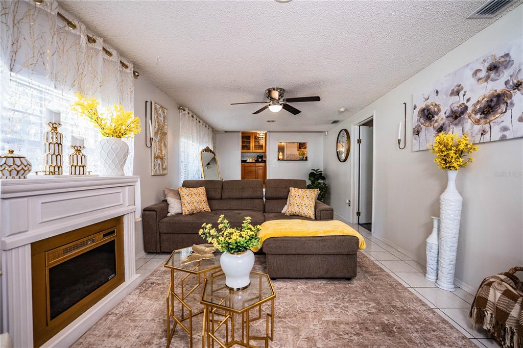 A living room features a brown sectional sofa, fireplace, and yellow floral accents — 8505 N CAMPBELL ROAD, LAKELAND, FL