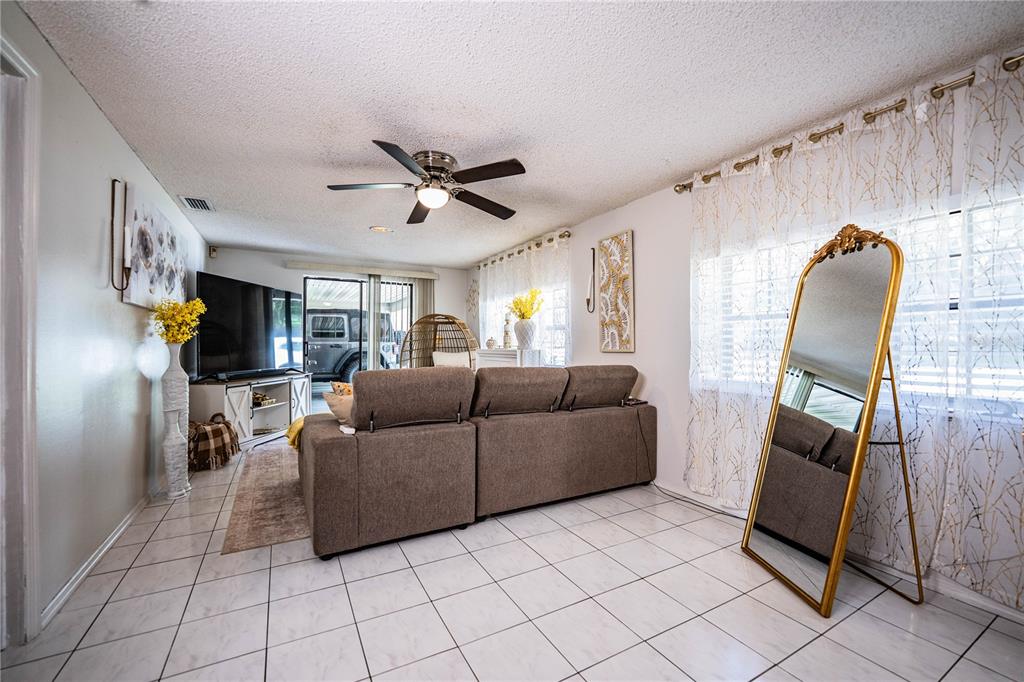 A living room features a brown sofa, a large floor mirror, and white tile flooring — 8505 N CAMPBELL ROAD, LAKELAND, FL