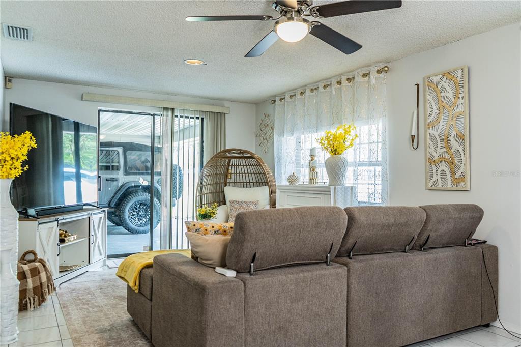 A living room features a brown sectional sofa, a ceiling fan, and a sliding glass door — 8505 N CAMPBELL ROAD, LAKELAND, FL