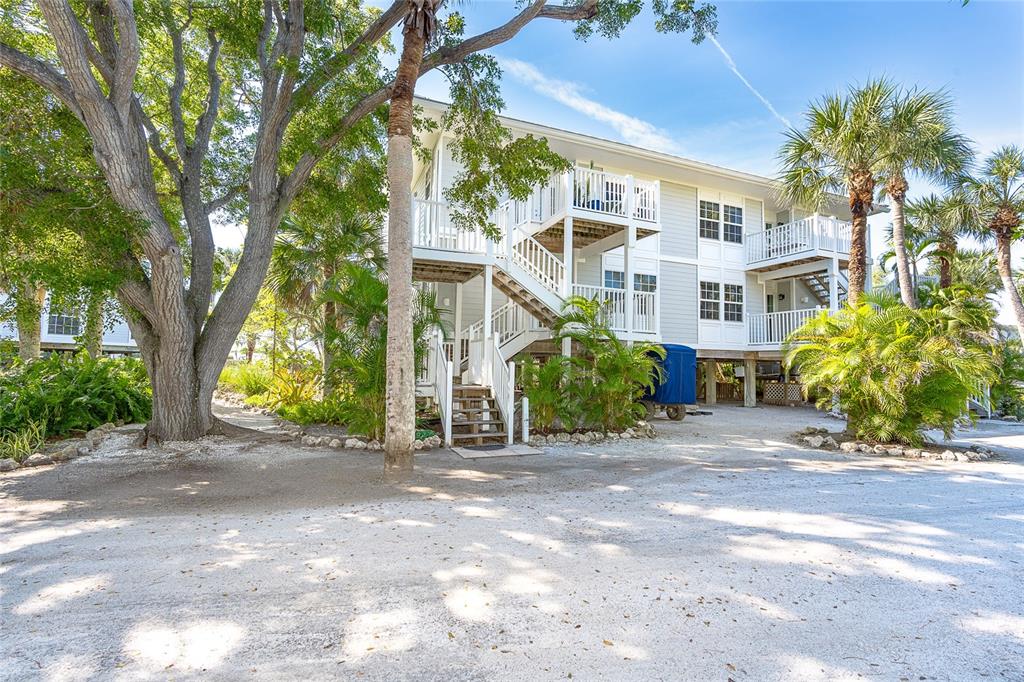 A multi-story building with white siding, elevated wooden staircases, and surrounding palm trees — 7536 PALM ISLAND DRIVE S UNIT 1524, PLACIDA, FL