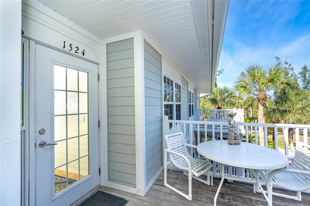 A white door with the number 1524 sits on a wooden balcony with outdoor furniture — 7536 PALM ISLAND DRIVE S UNIT 1524, PLACIDA, FL