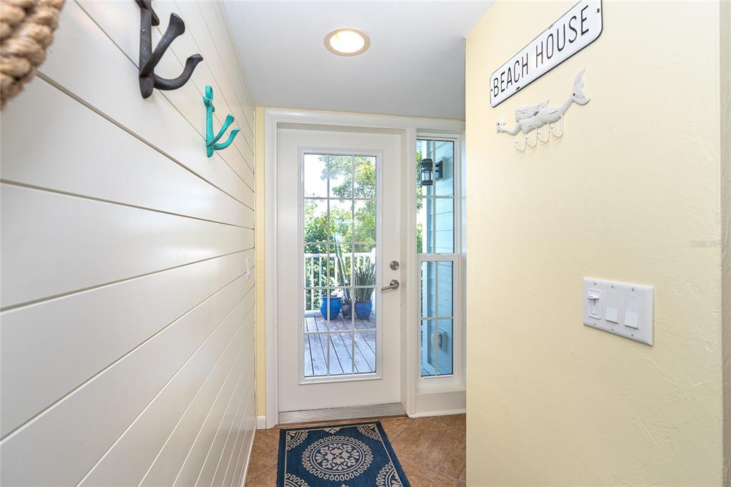 An entryway features white shiplap walls, a glass-paneled door, and a decorative beach-themed wall hook — 7536 PALM ISLAND DRIVE S UNIT 1524, PLACIDA, FL
