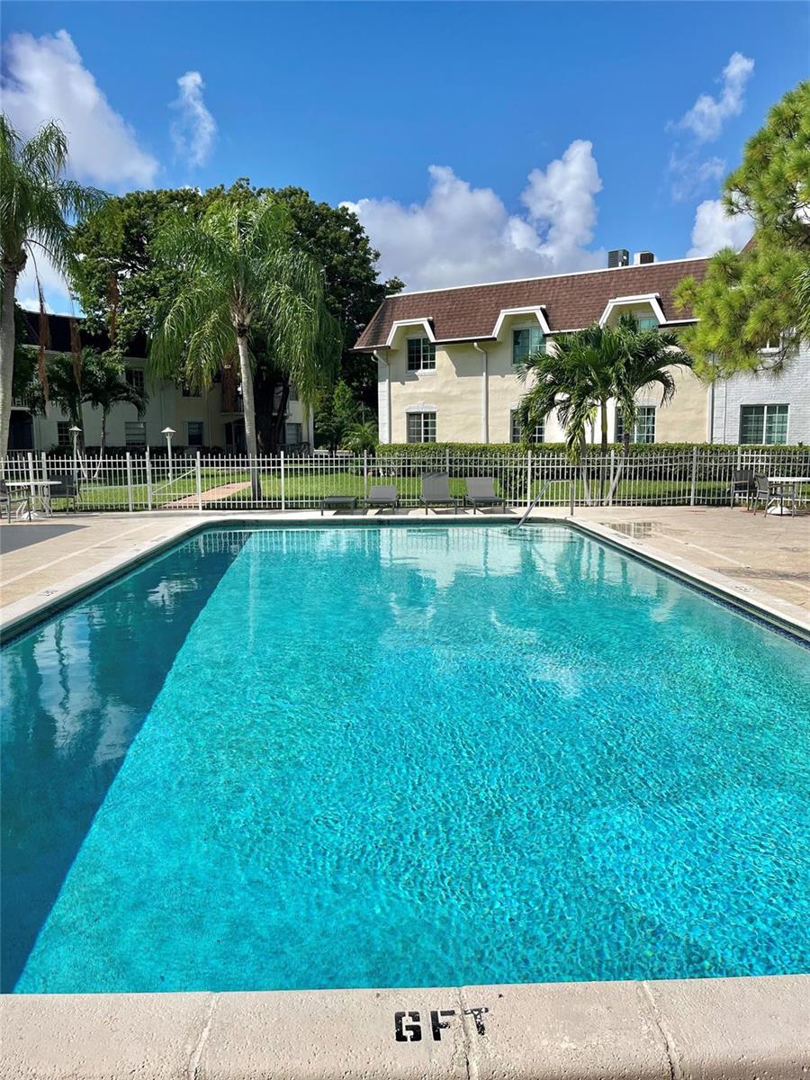A rectangular swimming pool sits in front of a multi-story apartment building with palm trees — 700 SE 2nd Avenue # 416, Deerfield Beach FL 33441, DEERFIELD BEACH, FL