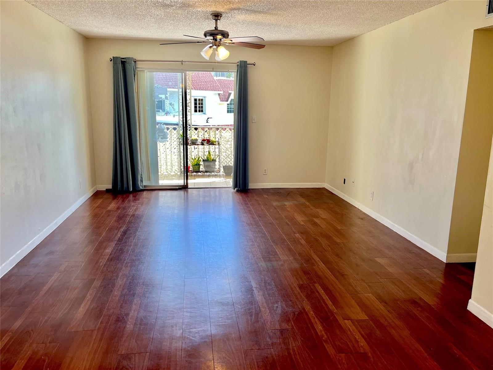 An empty living room features dark wood flooring, a ceiling fan, and sliding glass balcony doors — 700 SE 2nd Avenue # 416, Deerfield Beach FL 33441, DEERFIELD BEACH, FL